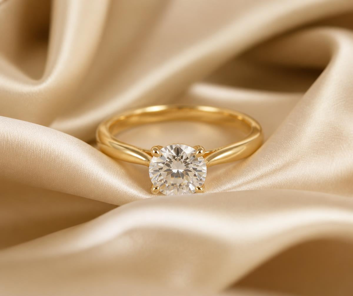 Gold solitaire diamond ring on cream silk